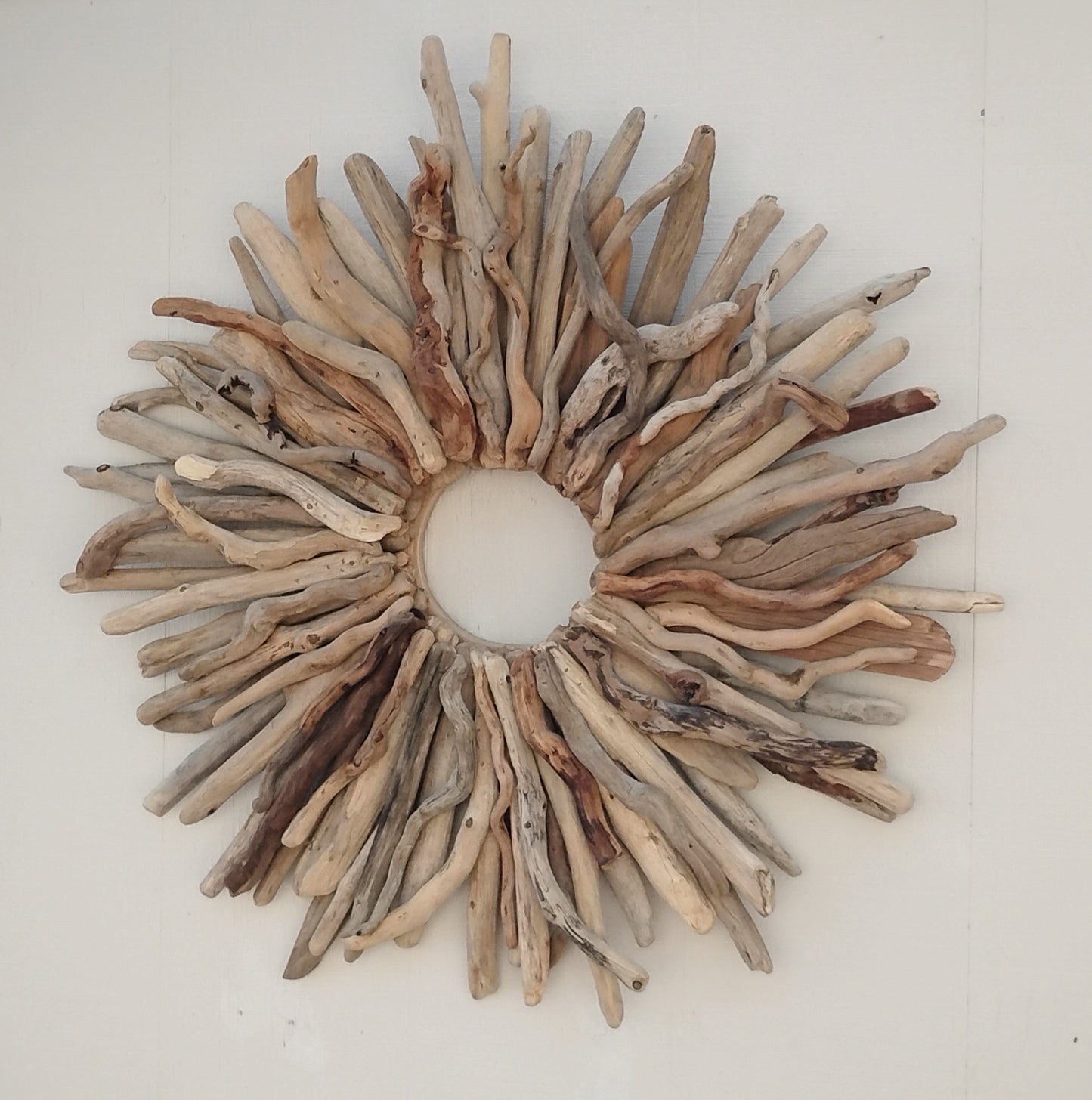 This large naturally weathered driftwood wreath adds a touch of organic elegance to any home. Handcrafted from real driftwood, the starburst design creates a unique and eye-catching focal point. Perfect for rustic or coastal decor, this wreath is a must-have for nature lovers.
A wreath handmade with real, natural driftwood sticks would look beautiful over the fireplace mantel or couch. Even the bedroom or entryway are great places to hang these one of a kind wreaths.