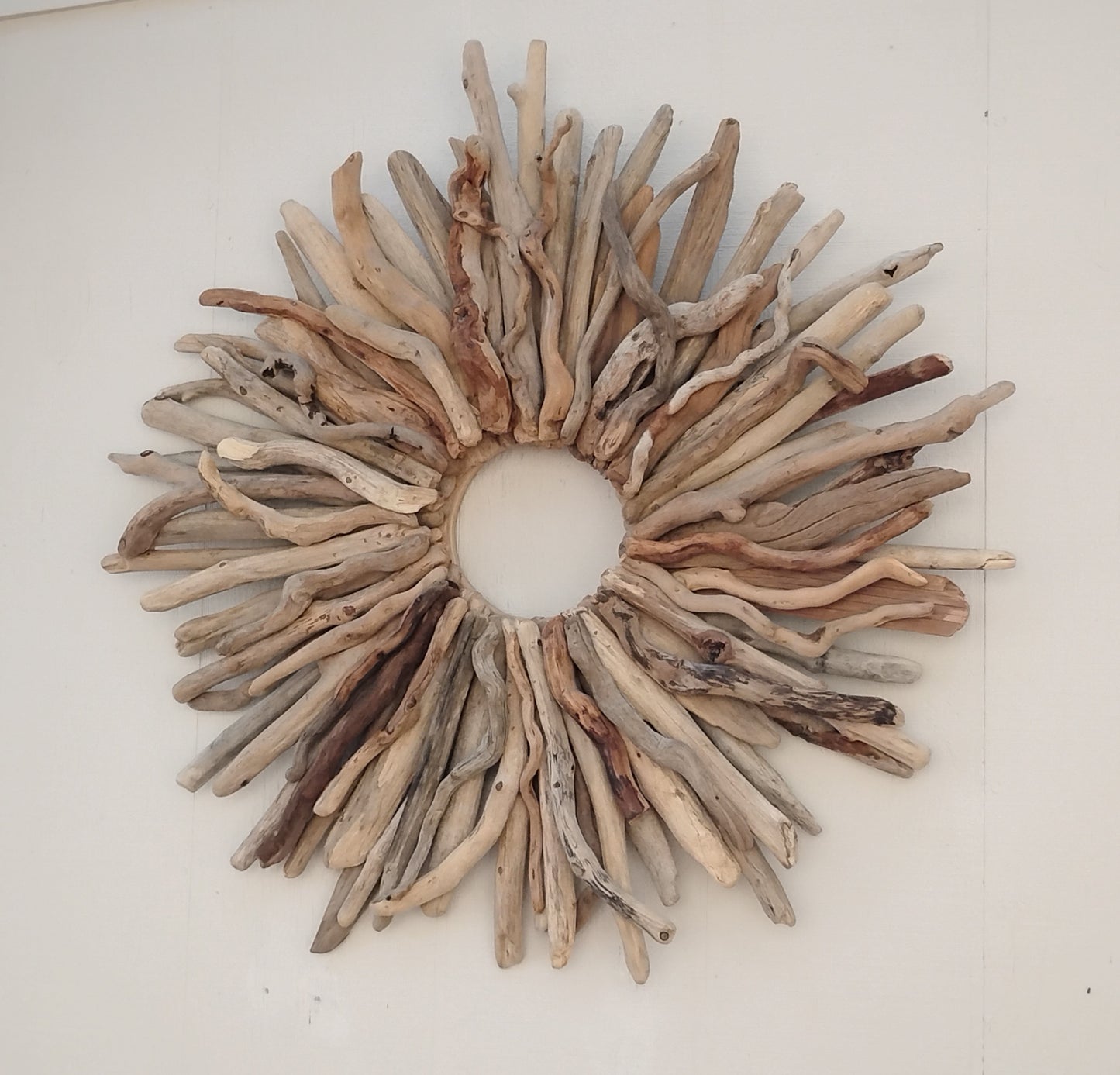 This large naturally weathered driftwood wreath adds a touch of organic elegance to any home. Handcrafted from real driftwood, the starburst design creates a unique and eye-catching focal point. Perfect for rustic or coastal decor, this wreath is a must-have for nature lovers.